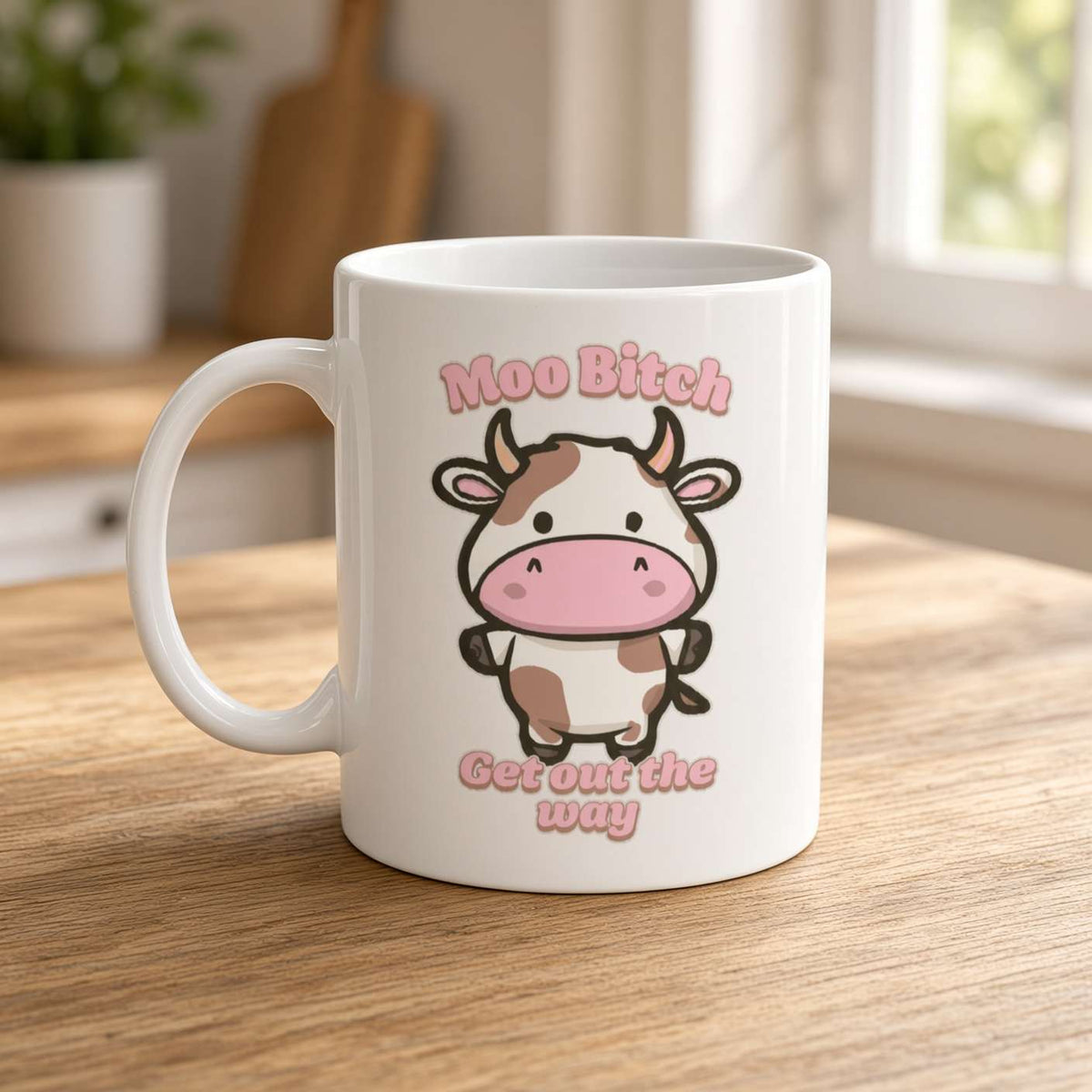 A white mug on a wooden kitchen counter shows a cute cartoon cow and pink text, “Moo Bitch, Get out the way,” creating a playful, cheeky tone.