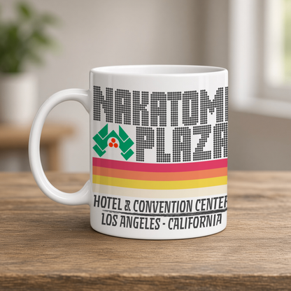 A white Nakatomi Plaza mug, labeled “Hotel & Convention Center, Los Angeles, California,” sits on a wooden table; its retro stripes feel nostalgic.