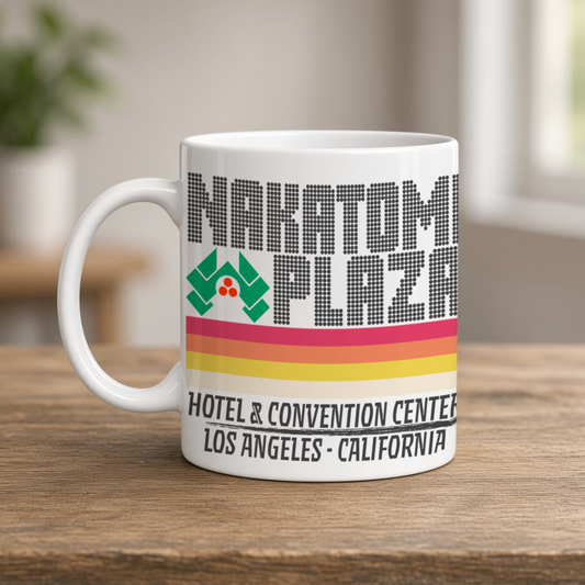 A white Nakatomi Plaza mug, labeled “Hotel & Convention Center, Los Angeles, California,” sits on a wooden table; its retro stripes feel nostalgic.