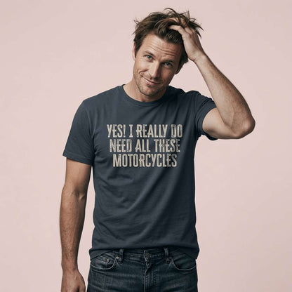 Man running a hand through his hair with a knowing half-smile while wearing a dark grey Yes! I Really Do Need All These Motorcycles t-shirt, classic relatable biker humour