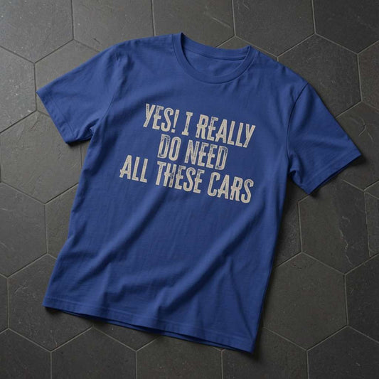 Bright blue Yes! I Really Do Need All These Cars t-shirt laid flat on dark hexagonal tiles, distressed text print perfect for any car-mad bloke