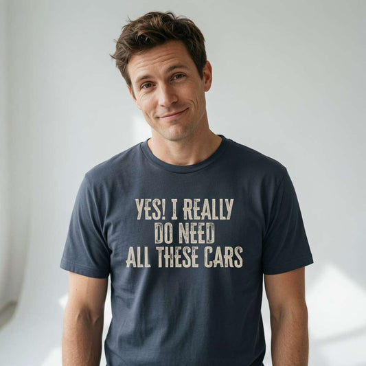 Man with a knowing half-smile wearing an ink grey Yes! I Really Do Need All These Cars t-shirt, witty and relatable slogan for dedicated car collectors