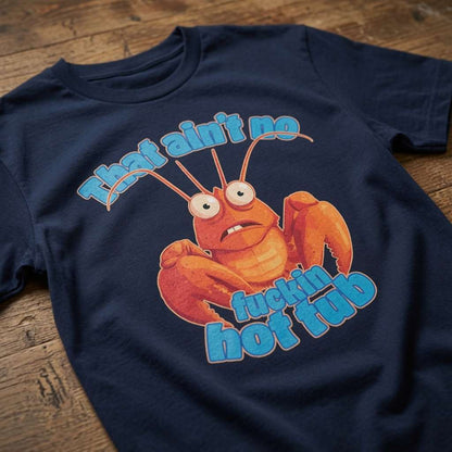 Navy That Ain’t No Fuckin Hot Tub t-shirt laid flat on a wooden surface showing the full cartoon lobster graphic, funny mens offensive lobster joke design full of pure attitude