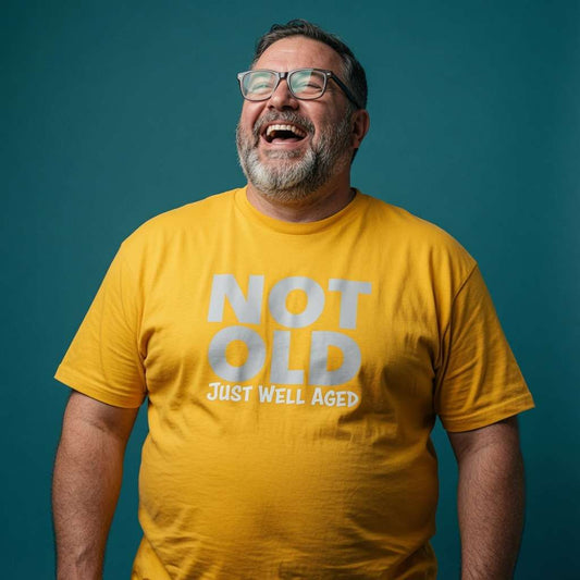 Man laughing with head tilted back while wearing a yellow Not Old Just Well Aged t-shirt, funny mens relatable grandad quote design full of pure attitude