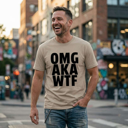 Man laughing in a beige OMG AKA WTF t-shirt while standing on a city street, witty banter slogan perfect for everyday reactions