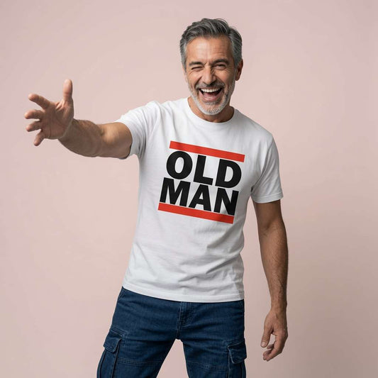 Grey-haired man laughing with one arm extended while wearing a white Old Man t-shirt with bold black text and orange bars, fun and witty cool dad slogan