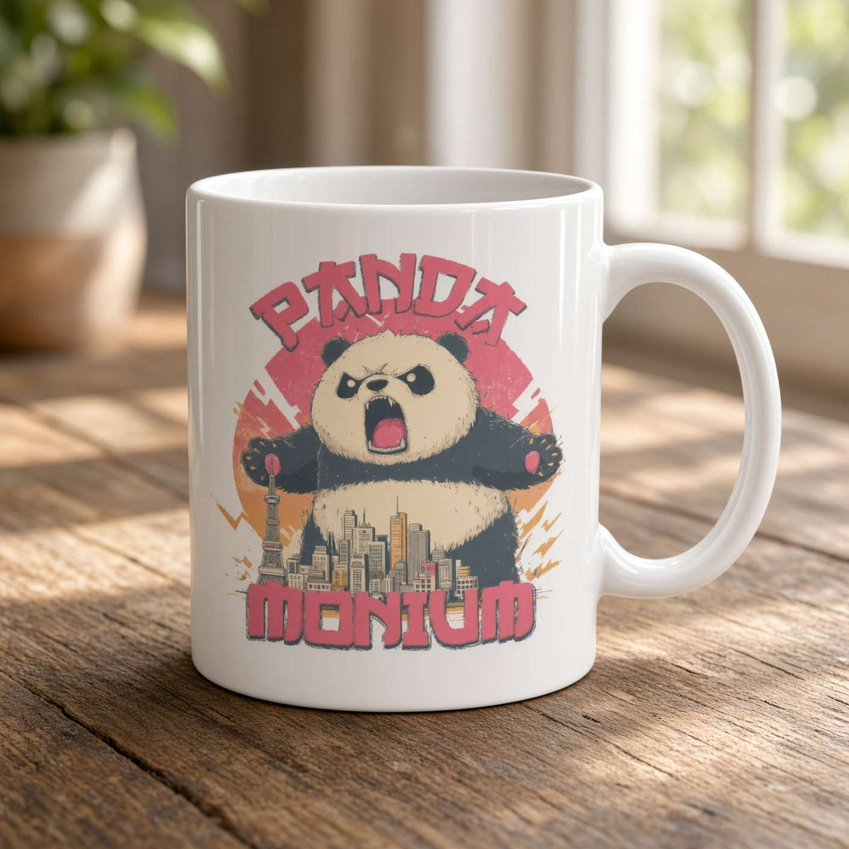 A white ceramic mug on a sunlit wooden table features an angry cartoon panda towering over a city, with bold red “PANDA MONIUM” lettering. The playful design feels energetic.