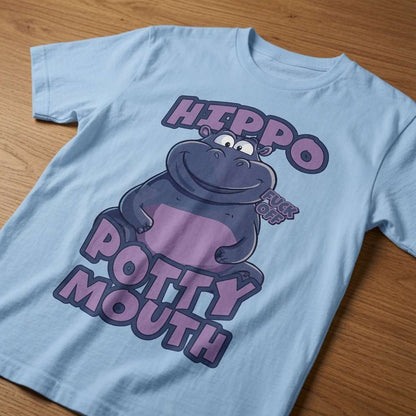 Light blue Hippo Potty Mouth t-shirt laid flat on a wooden surface featuring a smiling cartoon hippo with a “Fuck Off” speech bubble and the text “Hippo Potty Mouth”, witty and rude animal graphic design