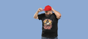 Man adjusting red cap, wearing a black funny t-shirt with a Jesus DJ graphic and 