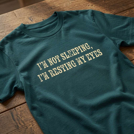 Stargazer I’m Not Sleeping, I’m Resting My Eyes t-shirt laid flat on a wooden surface showing the full slogan, fun ladies relatable slogan design full of pure attitude