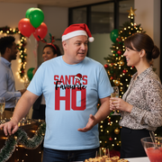 Man wearing a Santa hat and 'Santa's Favourite Ho' shirt at a festive gathering.