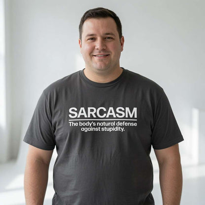 Man smiling while wearing a dark grey SARCASM – The body’s natural defense against stupidity. t-shirt, funny and cheeky mens witty slogan