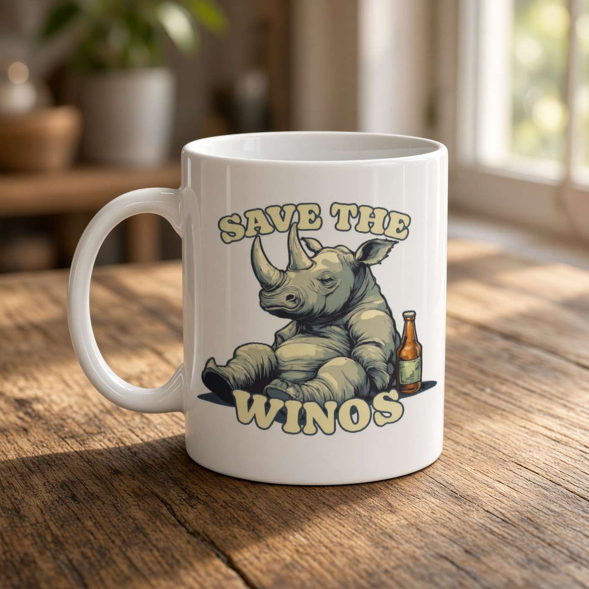 A white ceramic mug on a sunlit wooden table shows a relaxed cartoon rhino beside a beer bottle, with the slogan “Save the Winos,” in a playful, warm scene.