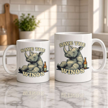Two white ceramic mugs on a sunlit marble counter feature a cartoon rhino, a wine bottle, and the phrase “Save the Winos,” creating a playful kitchen scene.