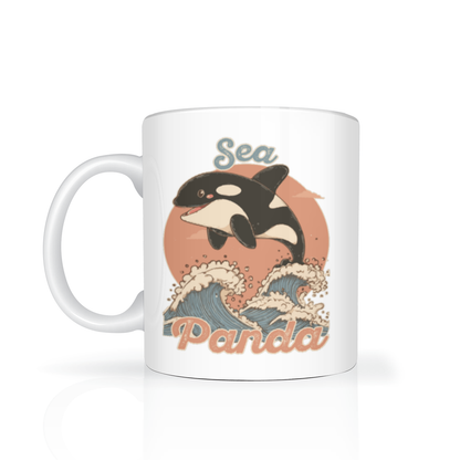 White ceramic mug featuring a playful orca jumping above stylized ocean waves, with “Sea Panda” lettering; cheerful, retro-inspired design.