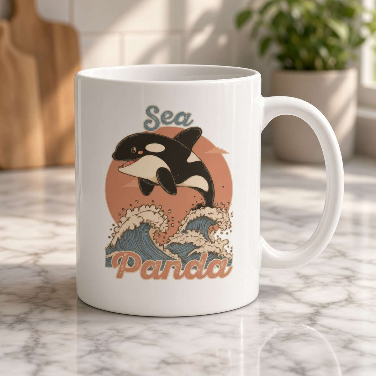 A white ceramic mug on a marble counter features a playful orca leaping over stylized ocean waves beneath the word “Sea,” in a warm, sunny kitchen.