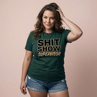 Woman running a hand through her hair in a green Shit Show Supervisor t-shirt, funny and relatable mum slogan that every chaos-managing woman will claim