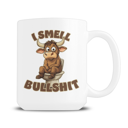 A white ceramic coffee mug featuring a cartoon bull sitting on a toilet with the text 'I SMELL BULLSHIT' in brown stylized lettering.