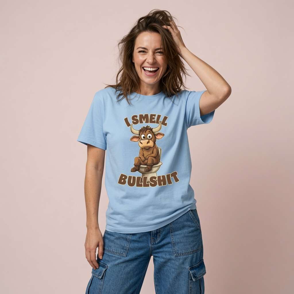 Woman laughing with one hand in her hair while wearing a sky blue I Smell Bullshit t-shirt featuring a cartoon bull on the toilet, funny and witty rude bull pun
