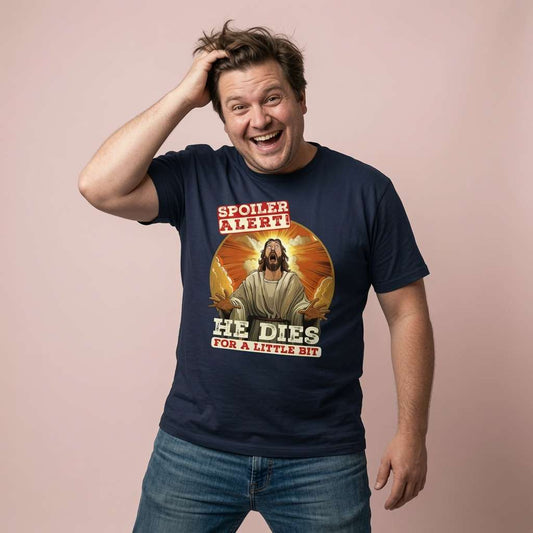 Man laughing with one hand in his hair while wearing a navy Spoiler Alert! He Dies for a Little Bit t-shirt featuring a shocked Jesus, funny and offensive Jesus graphic