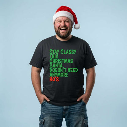 Bearded man in a Santa hat with hands in his pockets laughing in a black Stay Classy This Christmas Santa Doesn’t Need Anymore Ho’s t-shirt, funny mens witty xmas slogan that every festive lad will claim