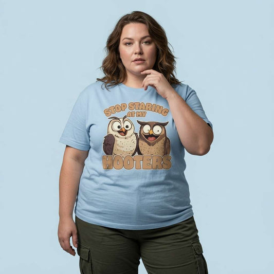 Woman resting a hand on her chin while wearing a sky blue Stop Staring at My Hooters t-shirt featuring two cheeky owls, fun and witty ladies owl graphic