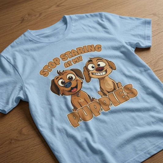 Sky blue Stop Staring at My Puppies t-shirt laid flat on a wooden surface showing the full pair of puppies, fun and cheeky puppy ladies design that every no-nonsense lady will claim