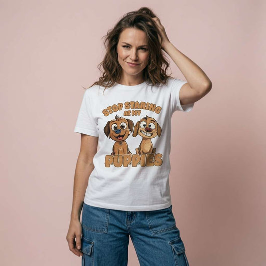 Woman resting a hand in her hair while wearing a white Stop Staring at My Puppies t-shirt featuring two cheeky cartoon dogs, ladies witty and funny dog relatable design