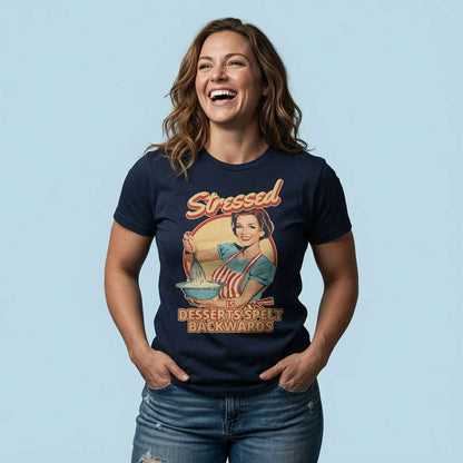 Woman laughing with hands in her pockets while wearing a navy Stressed is Desserts Spelt Backwards t-shirt featuring a retro housewife baking, ladies relatable stress graphic