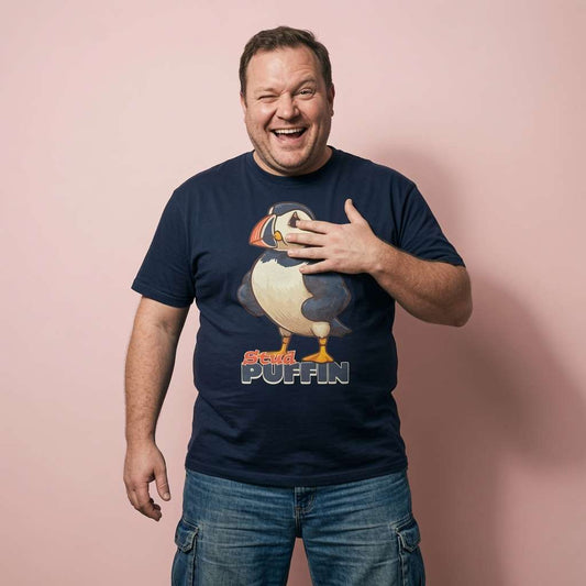 Man laughing and winking with a hand on his chest in a navy Stud Puffin t-shirt, funny and witty mens puffin pun full of pure attitude