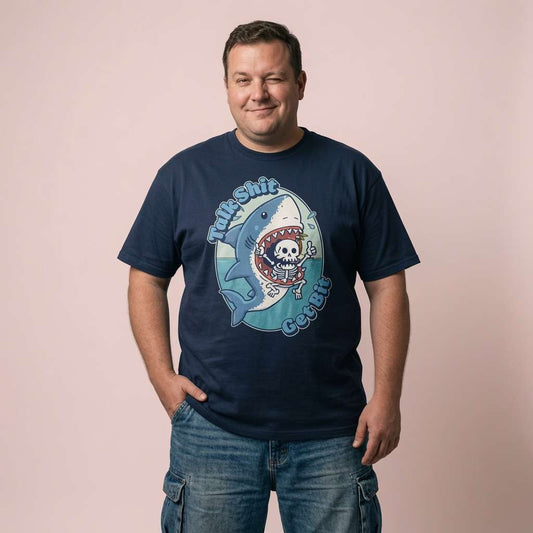 Man smiling and winking with hands in his pockets in a navy Talk Shit Get Bit t-shirt, fun and witty mens tattoo-style shark design full of pure attitude