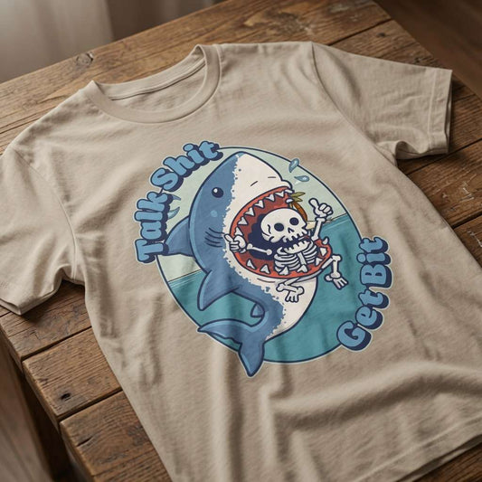 Stone Talk Shit Get Bit t-shirt laid flat on a wooden surface showing the full shark and skeleton graphic, funny mens witty shark pun that every cheeky lad will claim