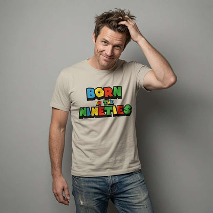 Man with one hand in his hair wearing a beige Born in the Nineties t-shirt, fun mens 90s video gamer inspired age-related design full of pure attitude