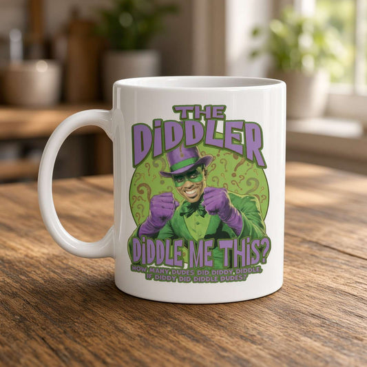 A white mug on a wooden kitchen counter features a grinning, green-and-purple comic-book character and playful “The Diddler” lettering, creating a quirky tone.