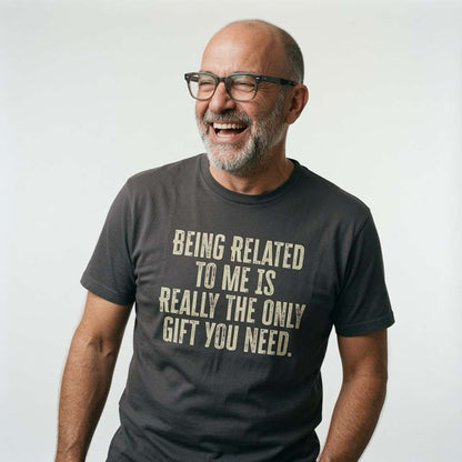 Older man with glasses laughing while wearing a khaki Being Related to Me is Really the Only Gift You Need t-shirt, fun slogan ultimate dad present full of pure attitude