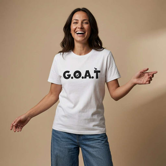 Woman laughing with arms outstretched while wearing a white G.O.A.T t-shirt with bold black lettering and tiny goat icons, witty ladies animal pun statement design