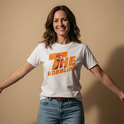 Woman smiling with arms outstretched while wearing a white The Gobbling t-shirt featuring a cartoon turkey head, funny ladies xmas day turkey design