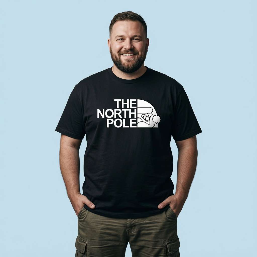 Bearded man smiling with hands in his pockets in a black The North Pole t-shirt, funny Santa pub banter shirt full of pure attitude