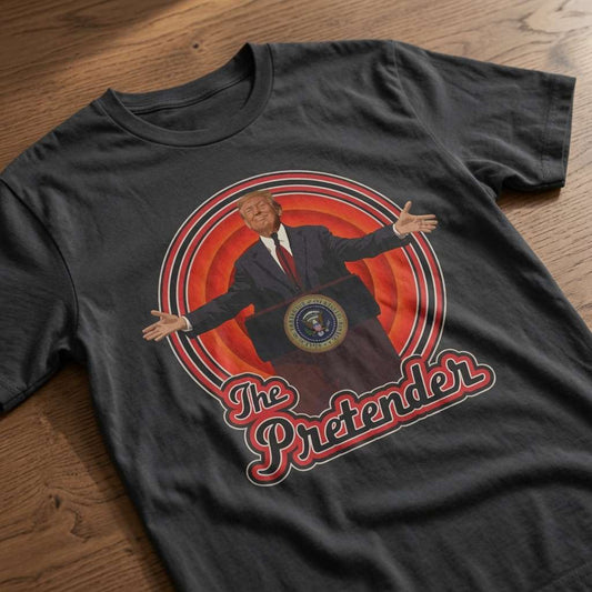 Black The Pretender t-shirt laid flat on a wooden surface showing the full Trump podium graphic, funny political satire tee that every cheeky lad will claim