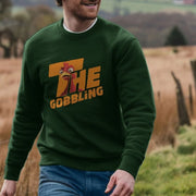 A man walking outside wears a green sweatshirt with a cartoon turkey and 