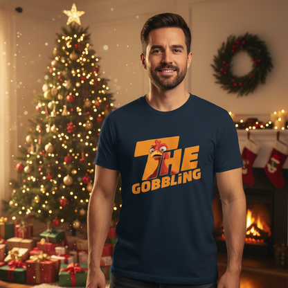 Man wearing a navy blue Christmas Turkey t-shirt with 'The Gobbling' design in a festive room with Christmas tree and fireplace.