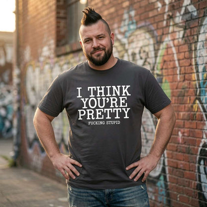 Man with a mohawk standing with hands on his hips outdoors while wearing an ink grey I Think You’re Pretty Fucking Stupid t-shirt, witty and funny offensive mens tee full of pure attitude