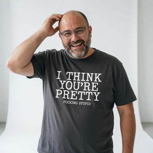 Man smiling with one hand on his head in a khaki I Think You’re Pretty Fucking Stupid t-shirt, rude and funny mens stupid statement design that every cheeky lad will claim