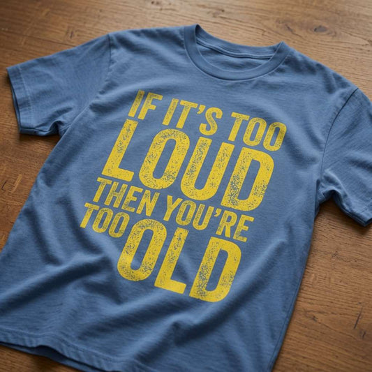 Blue If It’s Too Loud Then You’re Too Old t-shirt laid flat on a wooden surface showing the full distressed yellow slogan, witty age-related design that every no-nonsense lady will claim