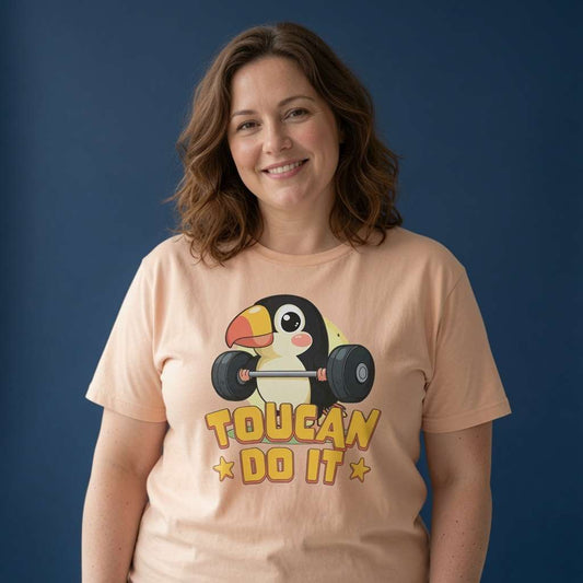 Woman smiling in a peach Toucan Do It t-shirt, cheeky pun and motivational bird design that every no-nonsense lady will claim
