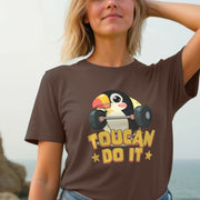 A woman wearing a brown Women's Animal T-shirt featuring a cute cartoon toucan lifting weights with the motivational phrase 