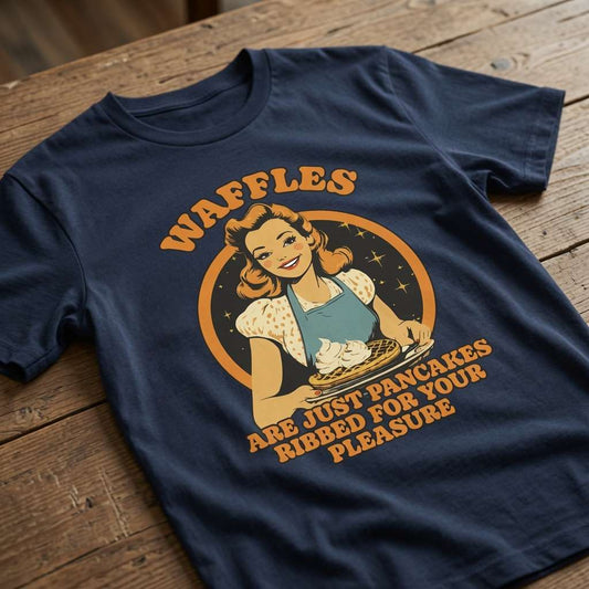 Navy Waffles Are Just Pancakes Ribbed for Your Pleasure t-shirt laid flat on a wooden surface showing the full retro waitress and waffle graphic, witty waffle dad joke design full of pure attitude