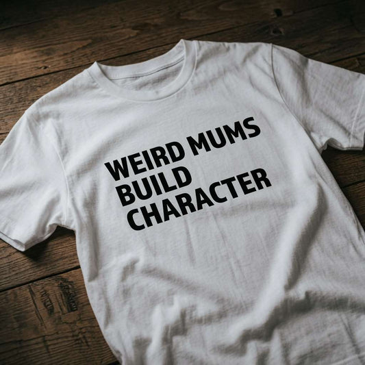 White Weird Mums Build Character t-shirt laid flat on a wooden surface showing the bold black text slogan, funny mums cheeky present design