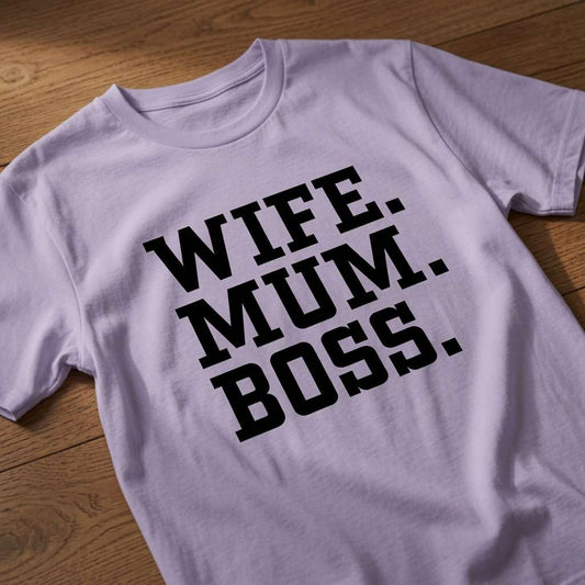 Lavender Wife. Mum. Boss. t-shirt laid flat on a wooden surface showing the bold black text slogan, the best Mothers Day gift shirt that every no-nonsense lady will claim