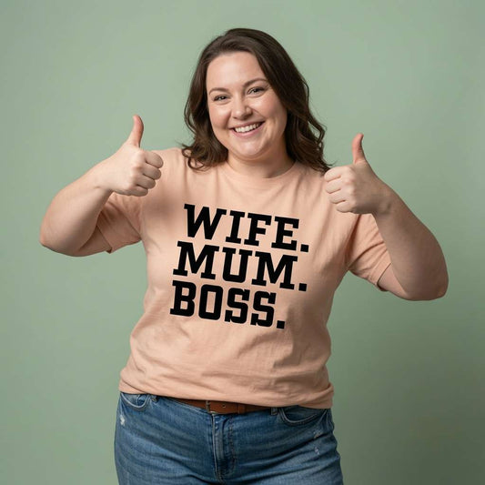 Woman smiling and giving a double thumbs-up while wearing a peach Wife. Mum. Boss. t-shirt, the ultimate Mothers Day shirt